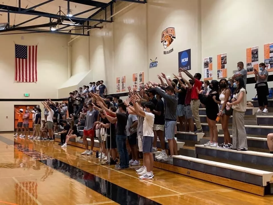 A large Braun Gym crowd raises their hands in support 