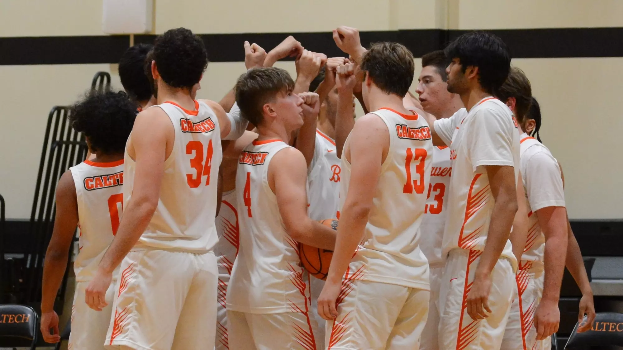Caltech Men's Basketball players raise their hands to the center of their huddle during a timeout