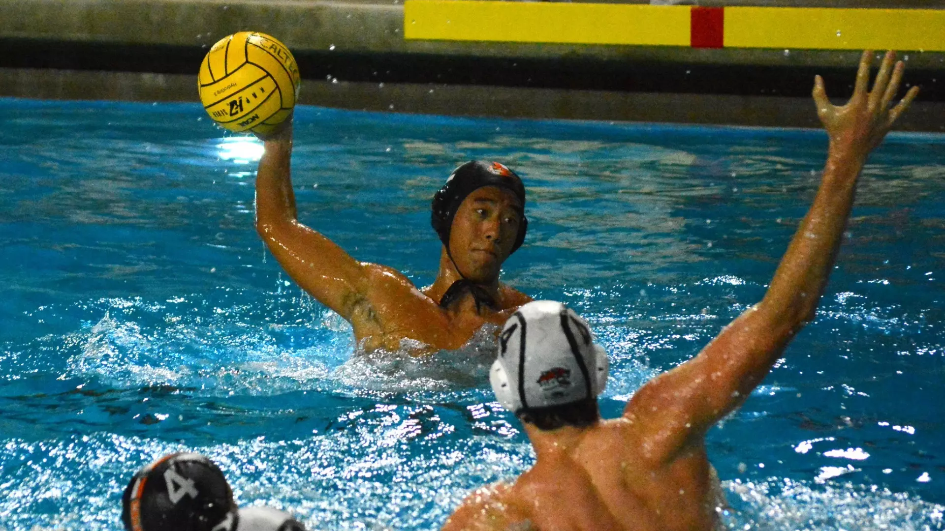Justin Hong winds up for a shot while an Occidental men's water polo player defends