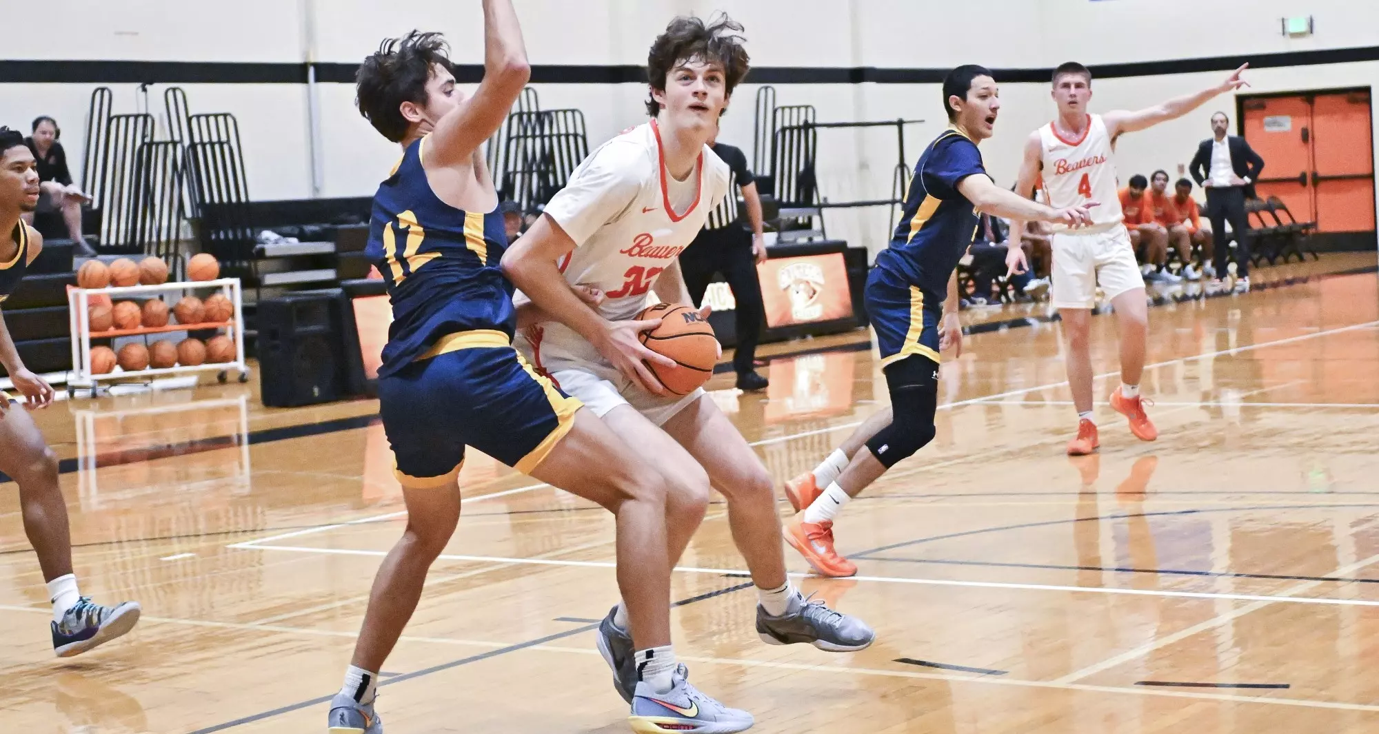 Finnegan Fancher drives against an opponent vs. UC Santa Cruz. Fancher holds the ball in both hands wearing a white jersey while contacting a defender in a  blue jersey who raises his right arm