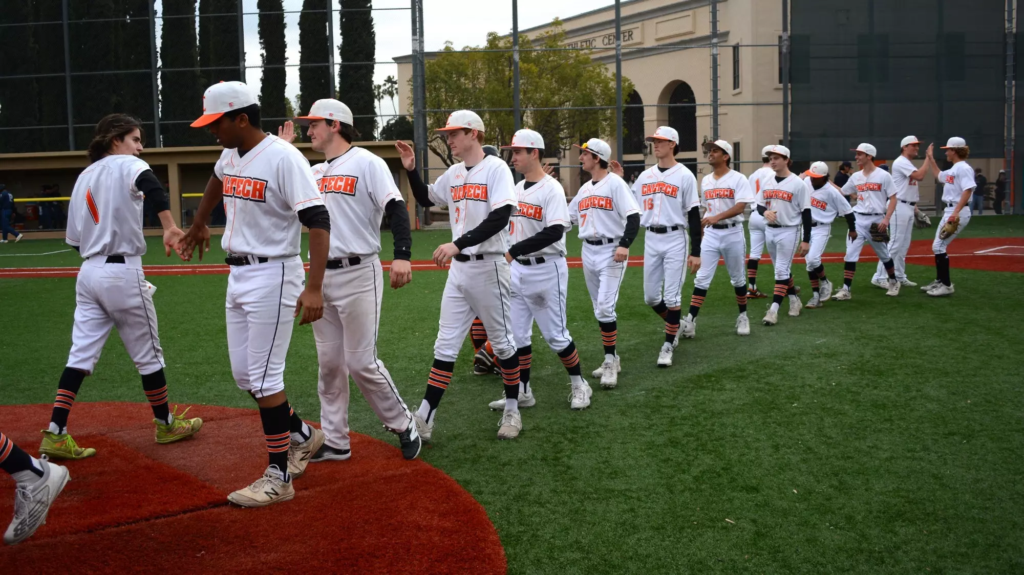 Caltech Baseball players high-fiving each other on the field after a win