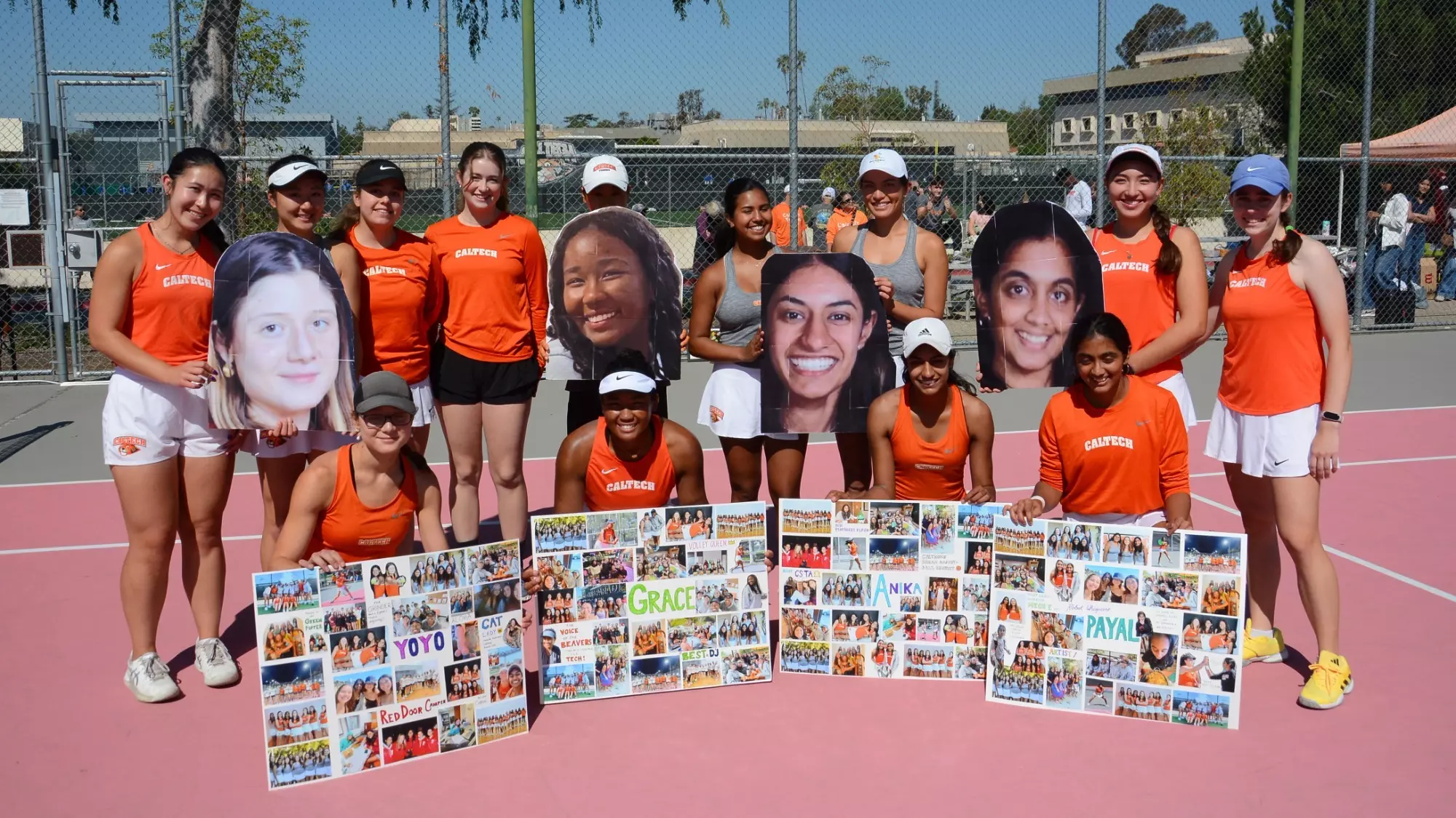 the four seniors of Caltech women's tennis kneel on the court with the rest of the team standing behind them. Each senior is holding a poster with their name in the center and dozens of photos from their time at Caltech posted around their name. the rest of the team comically holds giant headshots behind each senior. 