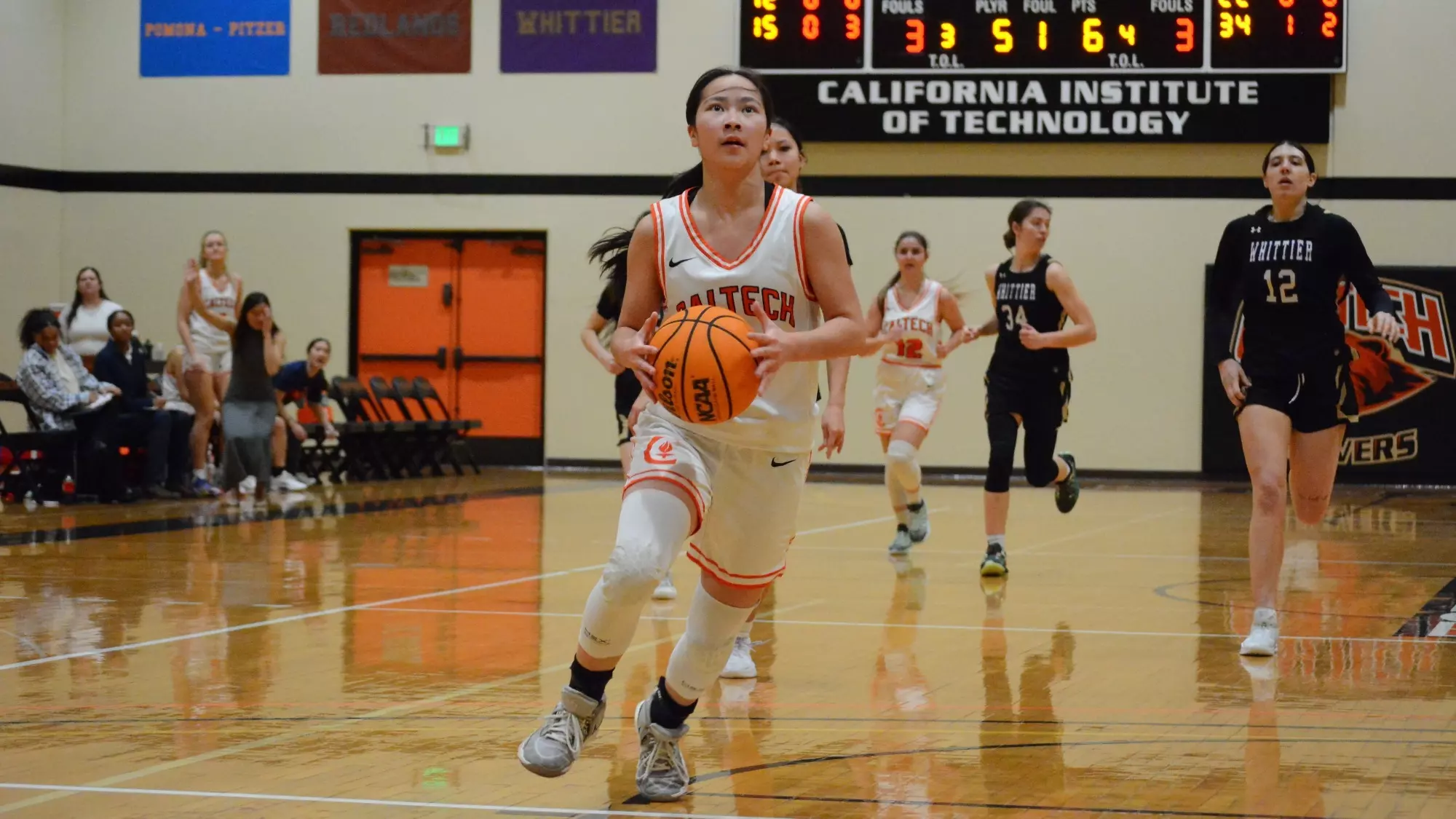Isabella Lo collects the ball with both hands in front of her as she prepares to rise up for an uncontested driving layup facing the under-the-hoop camera. 