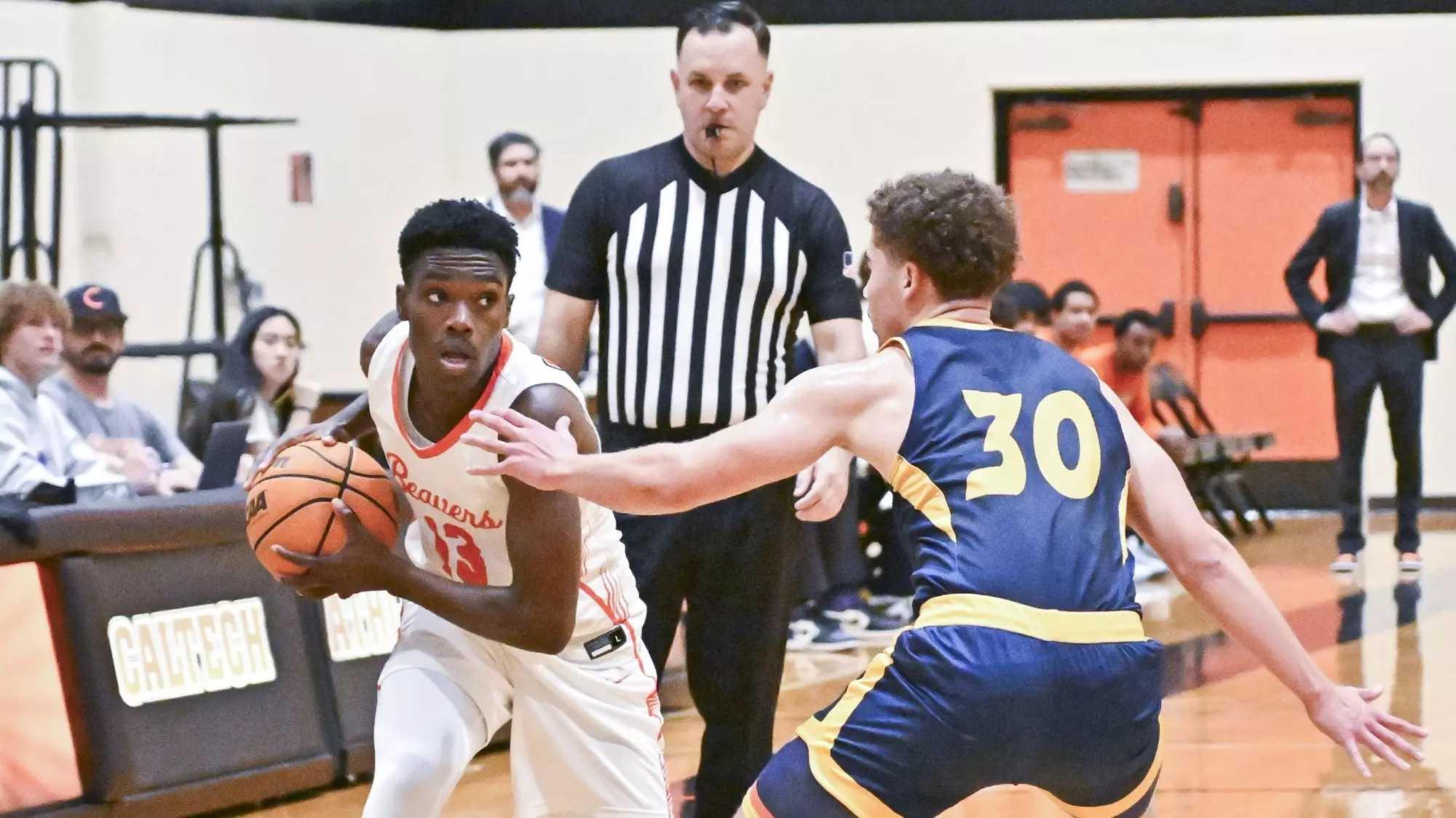 Josh Balami protects the ball with both hands as he looks past his defender near the sideline on the attacking end of the floor. 