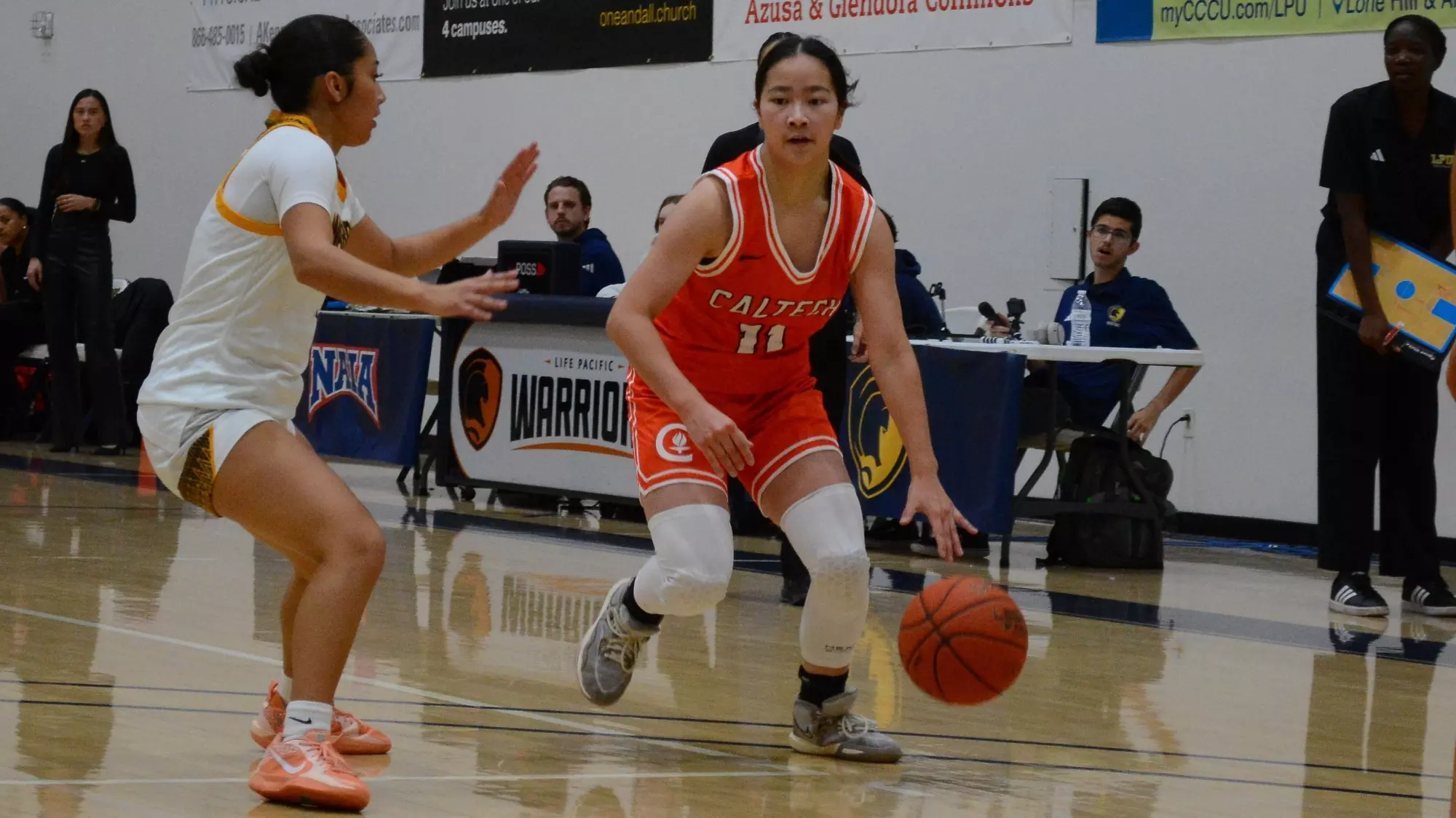 Isabella Lo looks between two defenders while dribbling the ball in her left hand at the three-point arc against Life Pacific. 