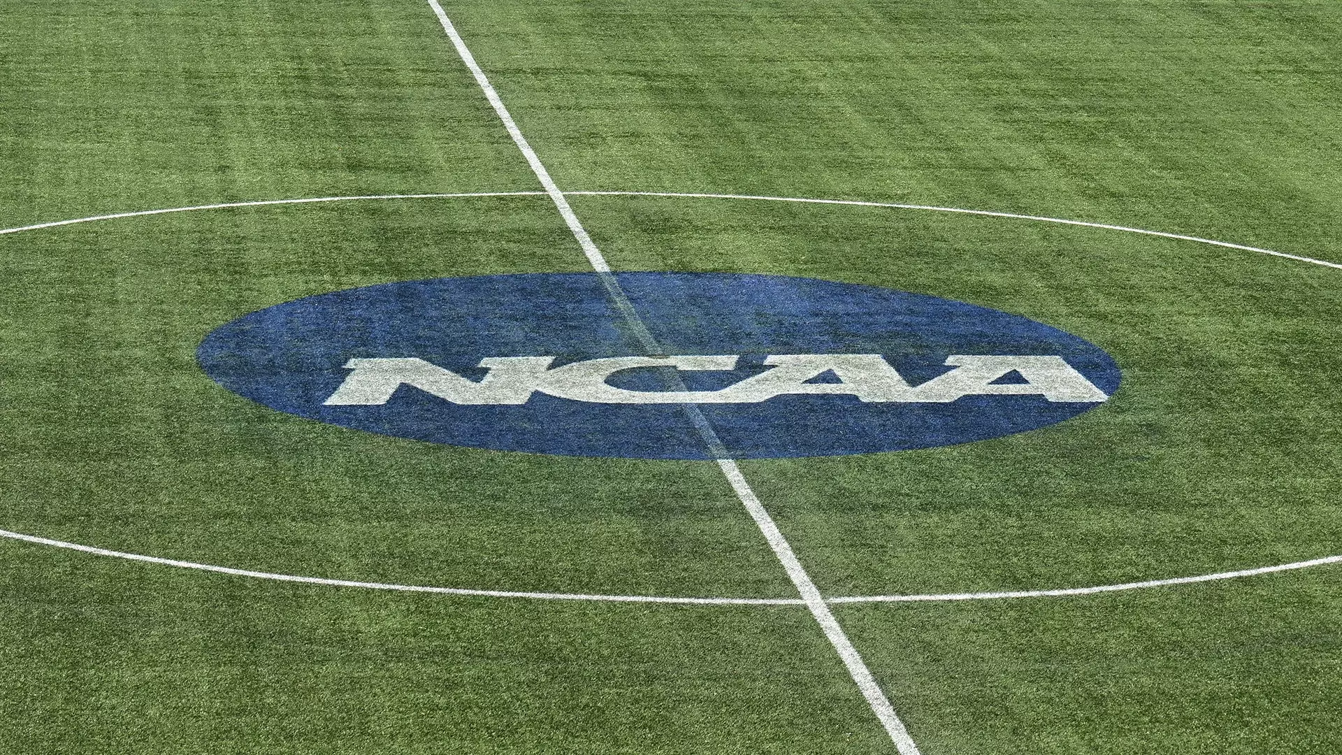 This is a photo of the NCAA blue disk logo on a soccer field.