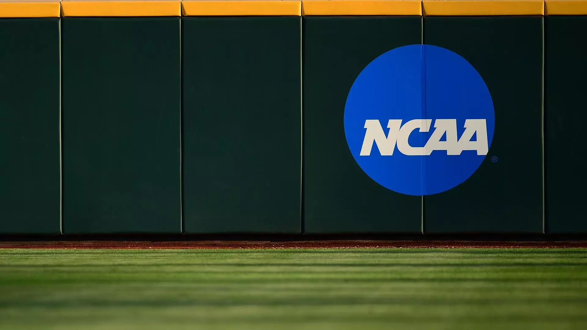 This is a photo of the NCAA blue disk logo on the outfield fence at the NCAA Men's College World Series.