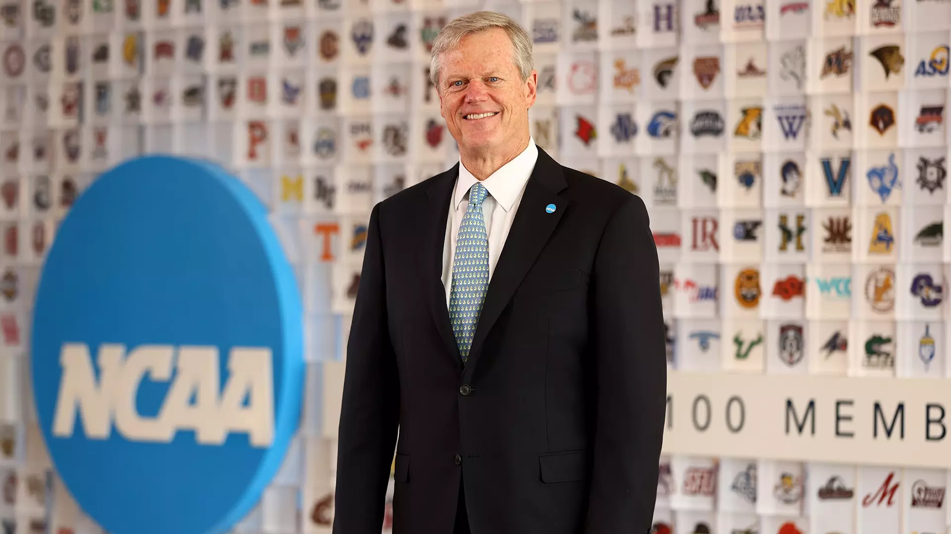 NCAA President Charlie Baker is shown in front of the membership logo wall in the lobby of the national office in Indianapolis.