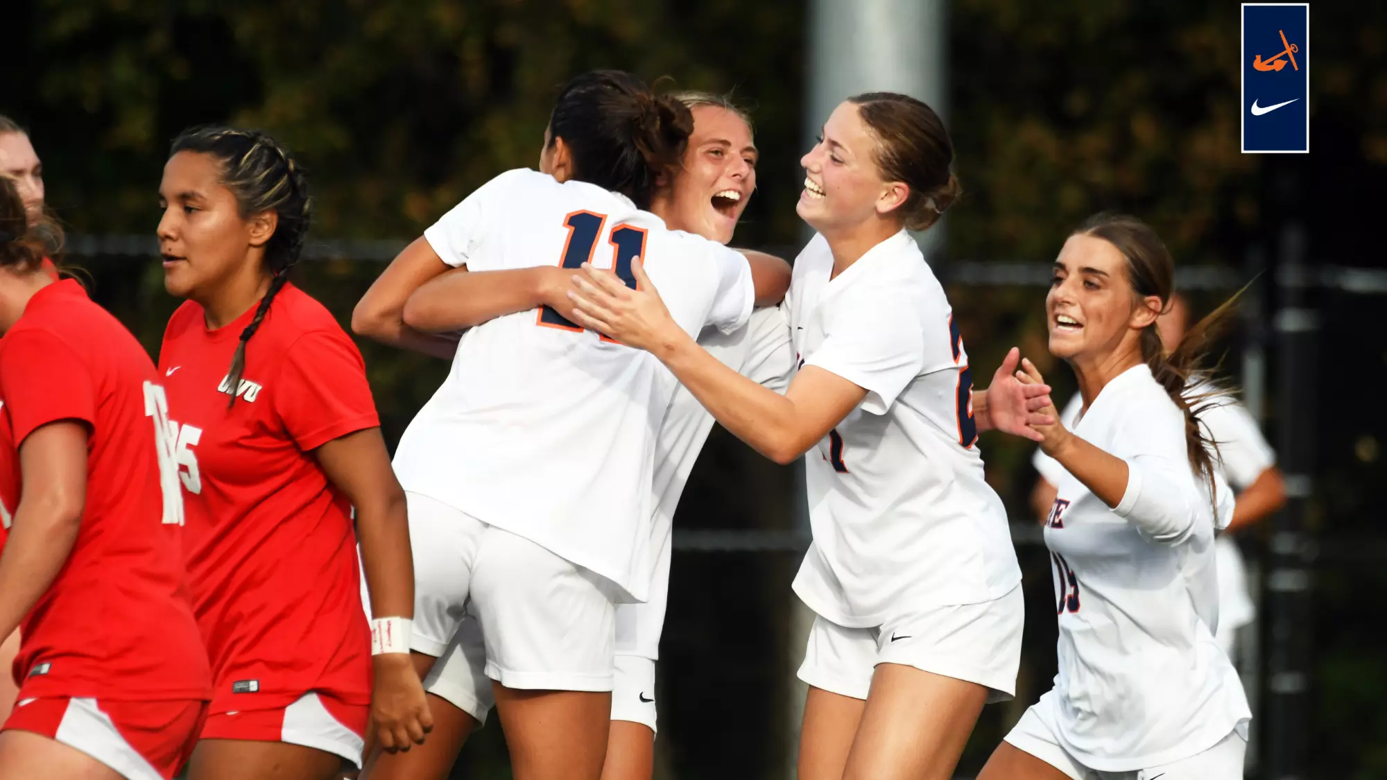 Three Hope women's soccer players leap together in a post-goal celebration.