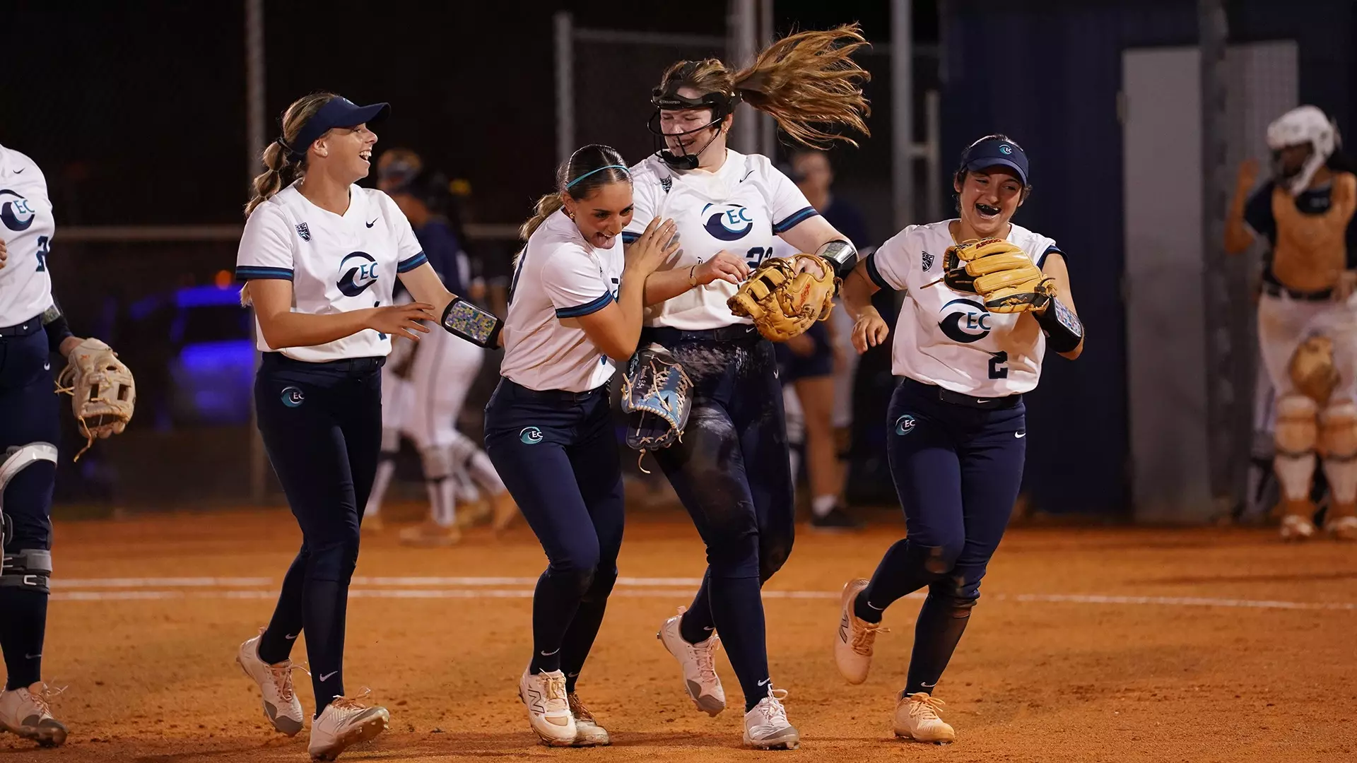 Softball players celebrating and laughing on field 