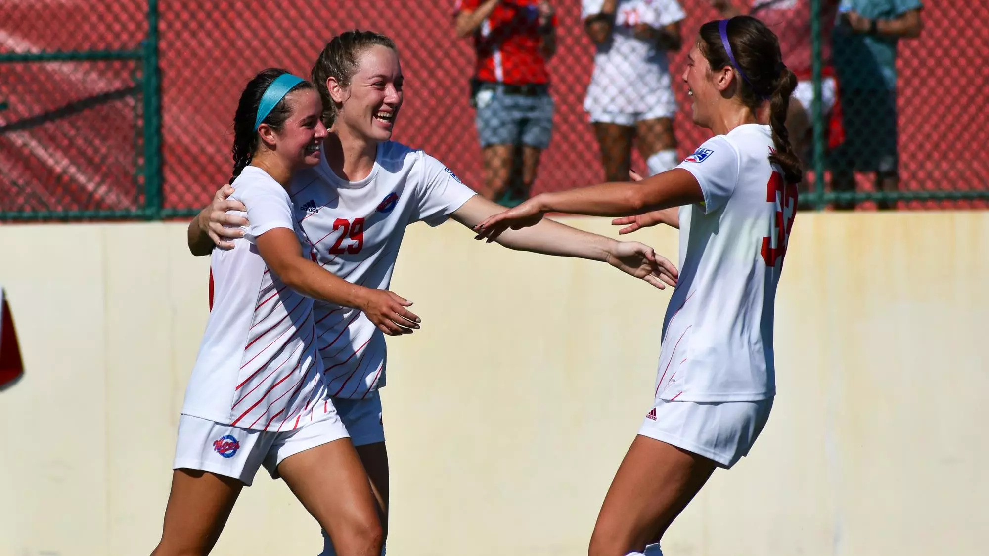women's soccer players celebrate goal in 2021 preseason game