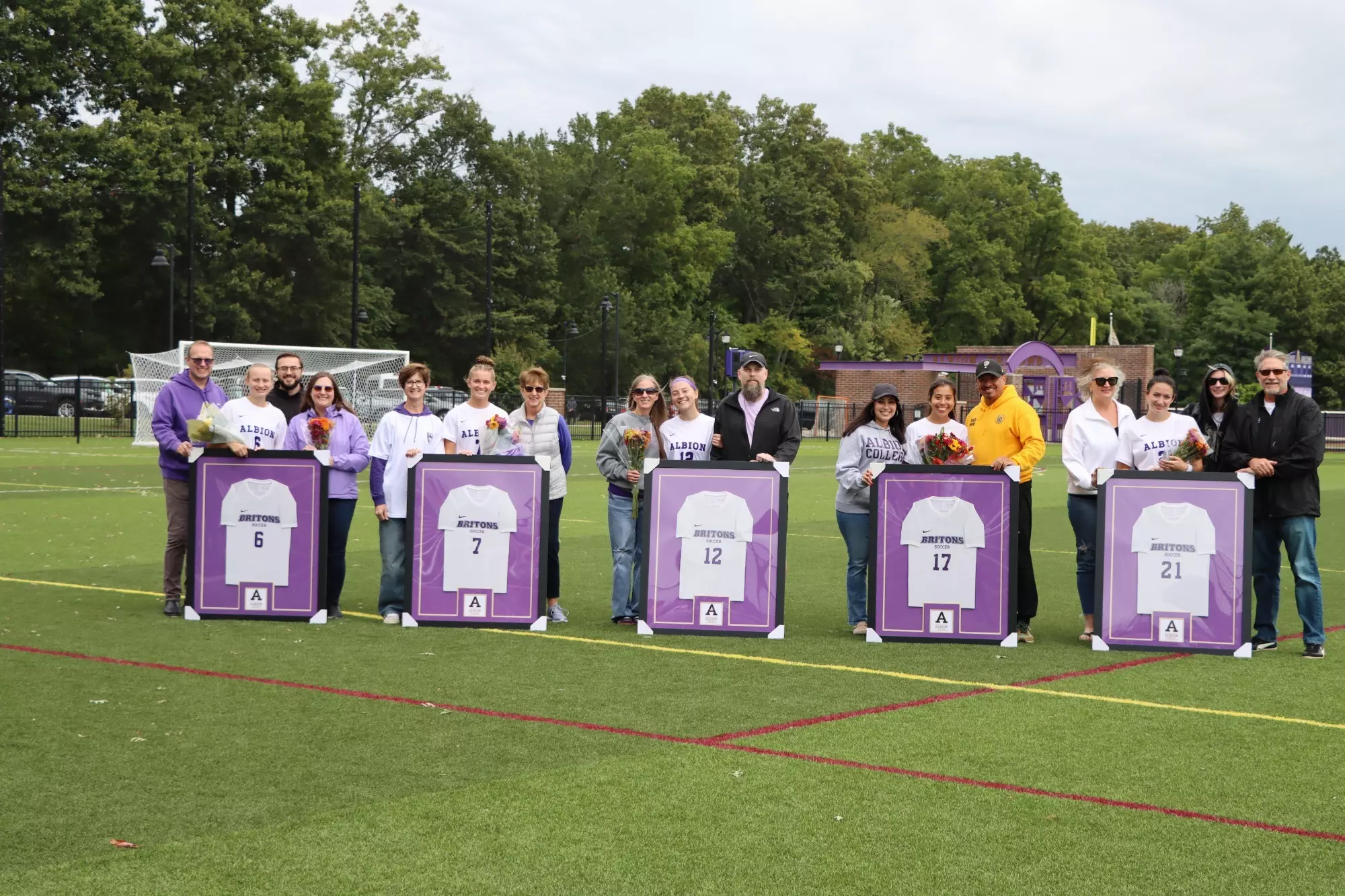 Women's Soccer seniors and family members pose for a photo on a turf field
