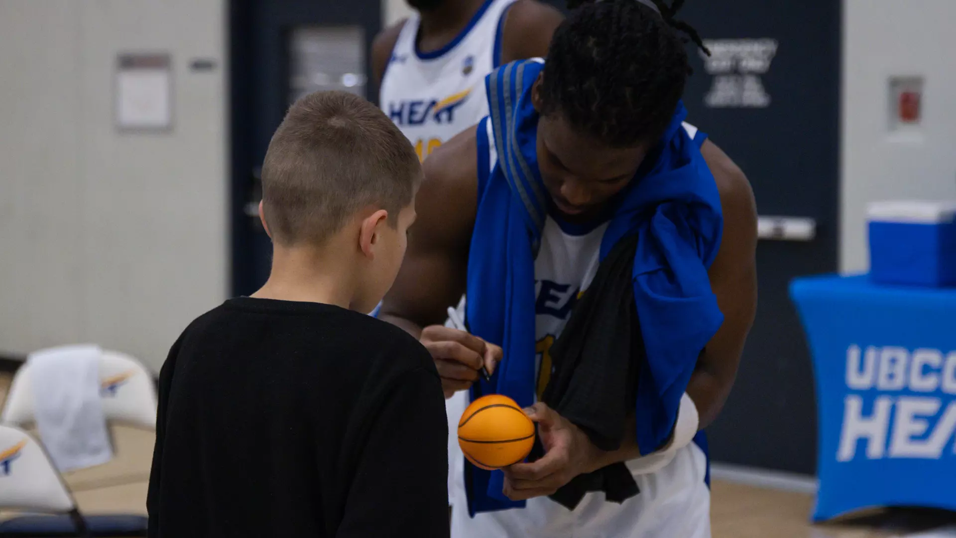 Jalen Shirley signs a mini basketball for a young fan after a home game
