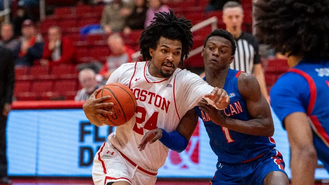 Miles Brewster dribbles toward the hoop while guarded by an American defender.