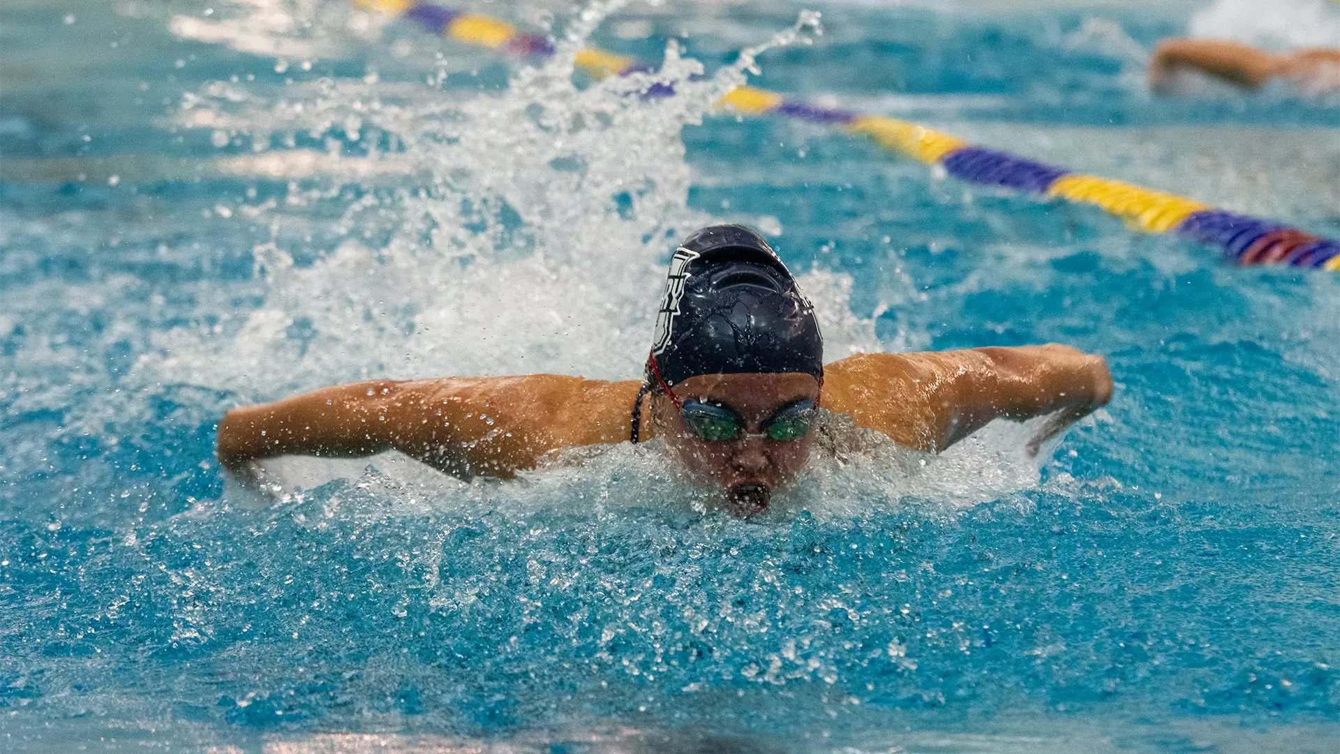 UMary swimmer races with splashes surrounding