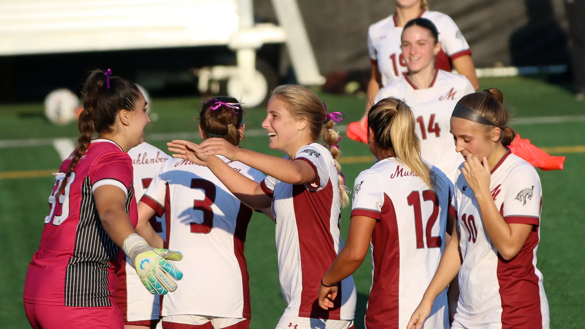 women's soccer players in white jerseys celebrate a goal