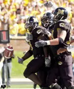 Missouri running back Damien Nash, left, tosses the ball to an official as he is congratulated by teammmates after scoring a touchdown during the first quarter against Colorado on Saturday, Oct. 2, 2004, in Columbia, Mo.