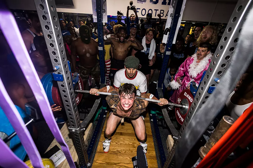 Members of the Duke football team cheer on a teammate during back squats