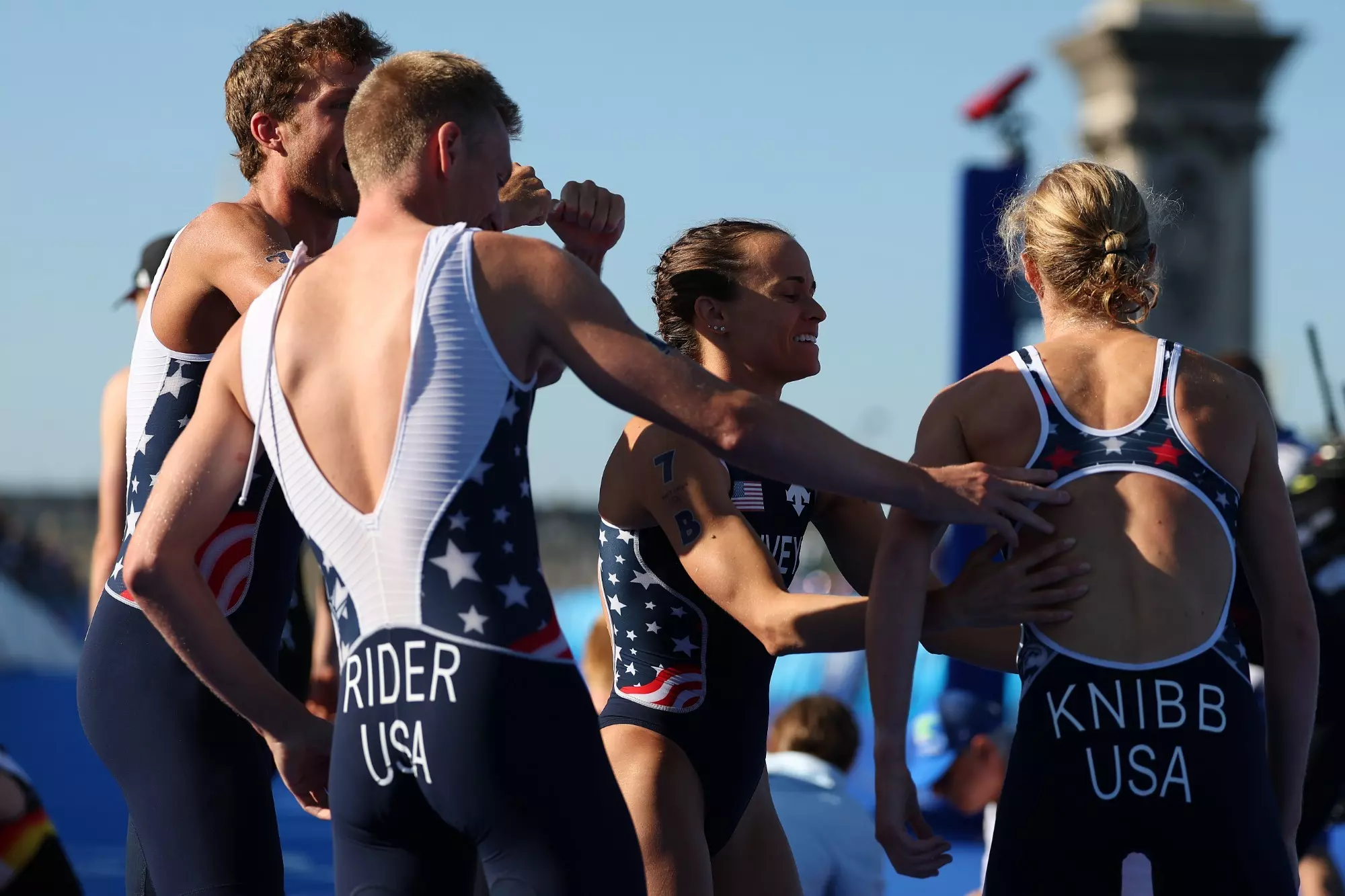 PARIS, FRANCE - AUGUST 05: Taylor Knibb of Team United States is congratulated by teammates after winning the Silver medal for Team United States following the Mixed Relay on day ten of the Olympic Games Paris 2024 at Pont Alexandre III on August 05, 2024 in Paris, France. (Photo by Al Bello/Getty Images)