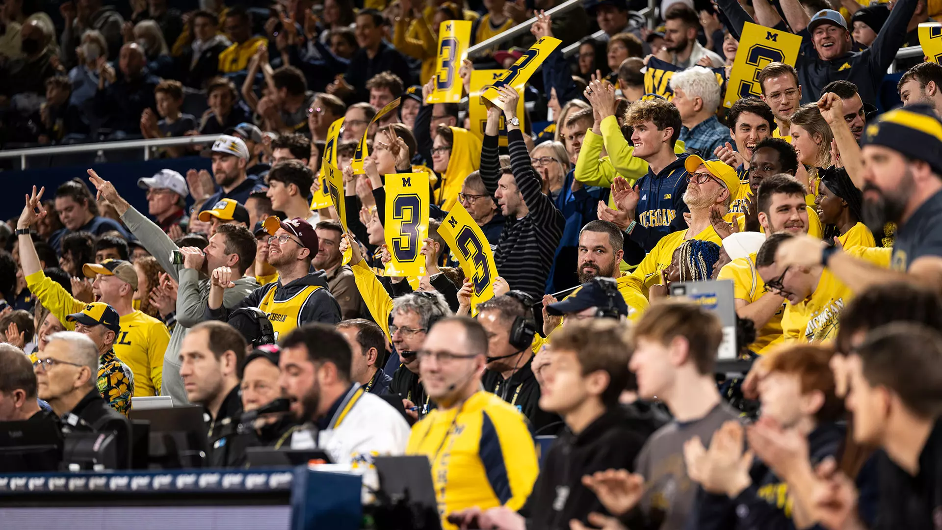 Fans at Crisler Center holding 3-point cards