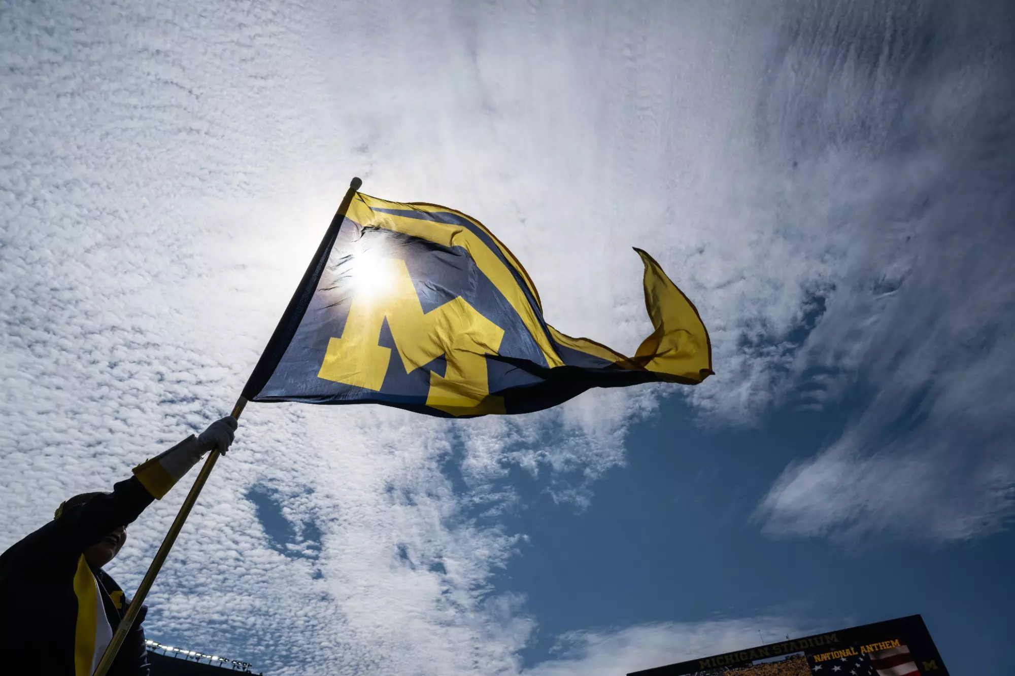 Band member holds a Michigan Flag with blue sky in background