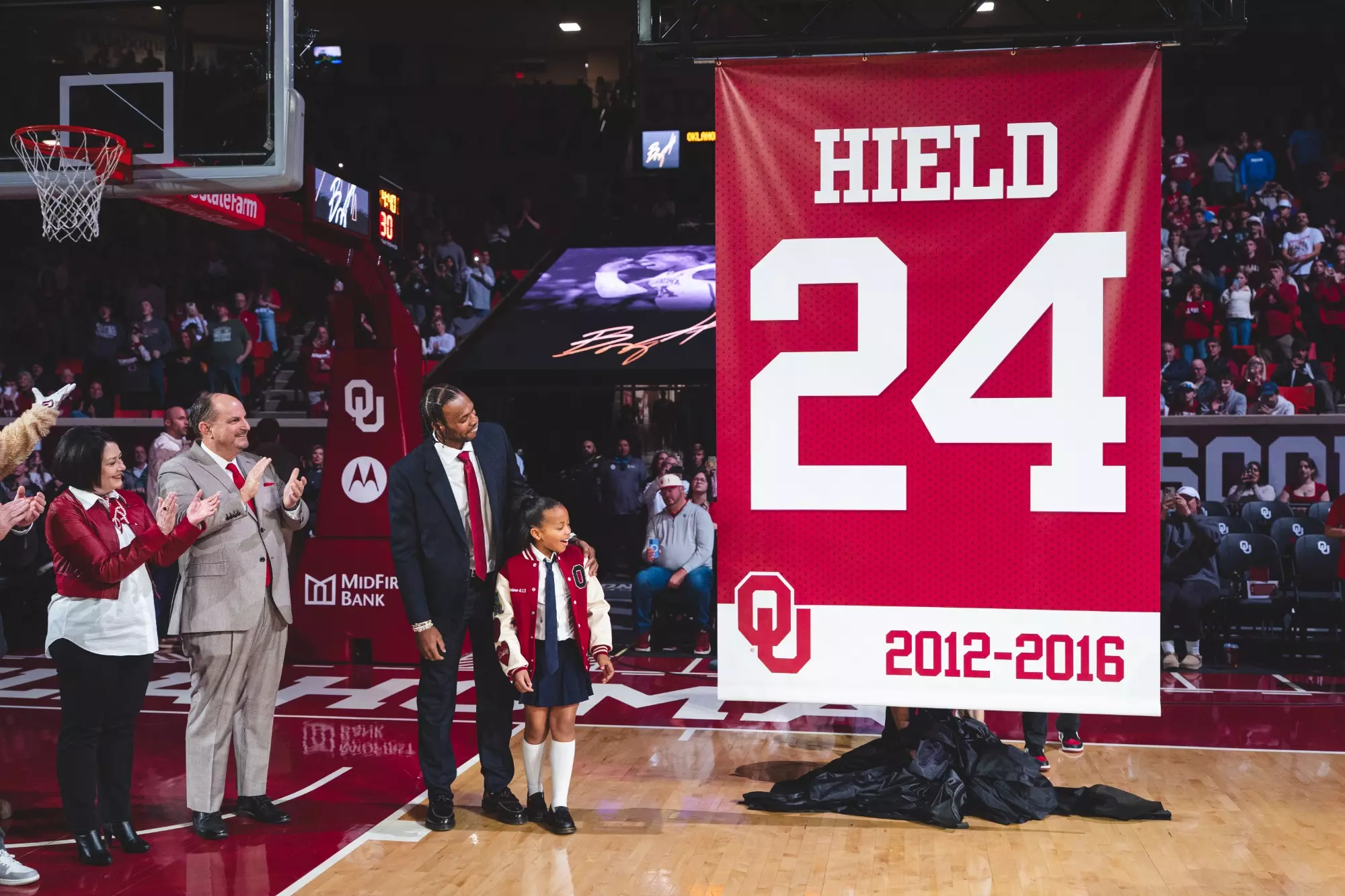 Photo showing Buddy Hield and others looking on at his No. 24 Hield jersey that will hang in the rafters