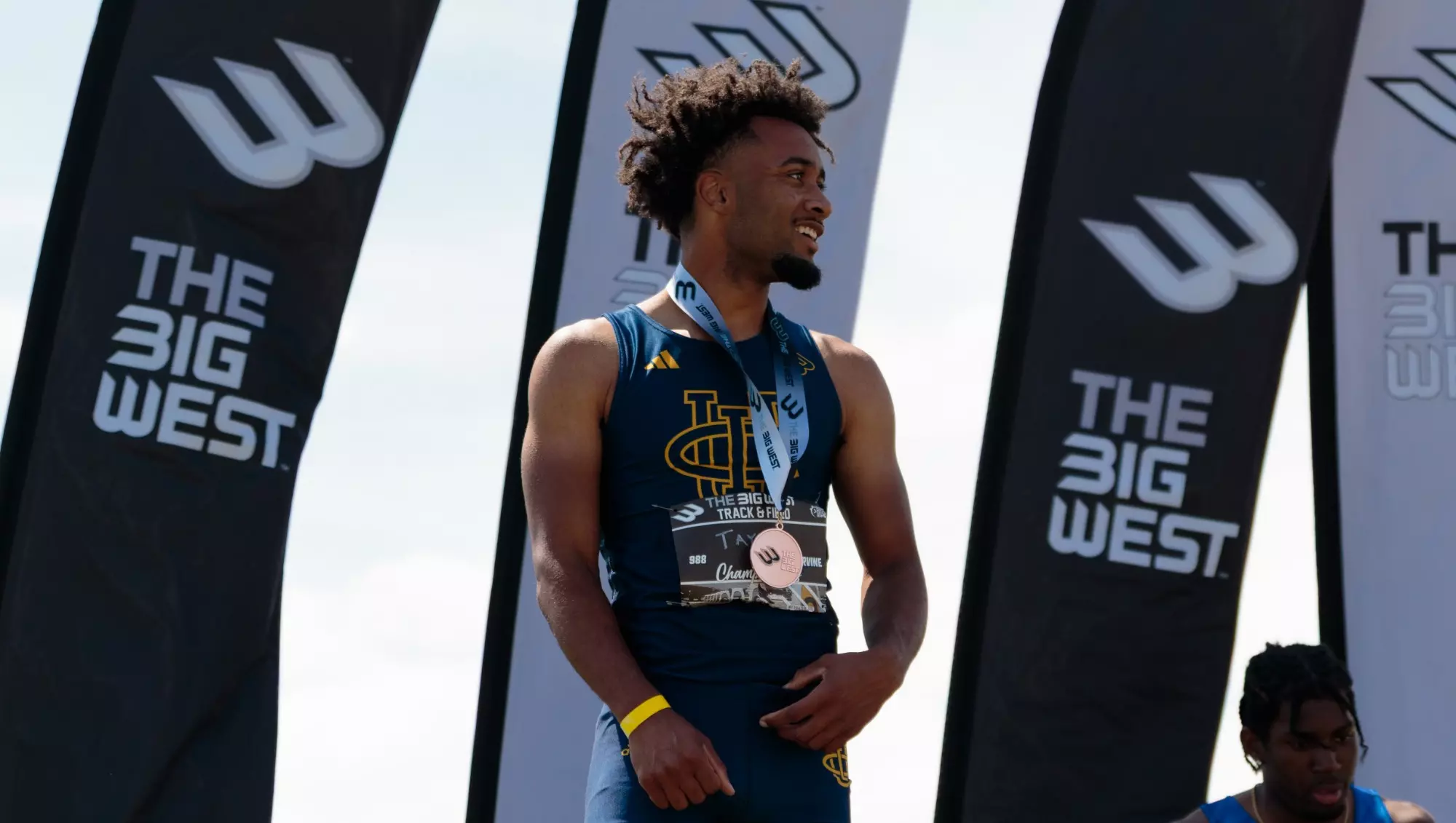 AJ Taylor stands on the podium after winning bronze in the men's 110-meter hurdles at the Big West Championships.