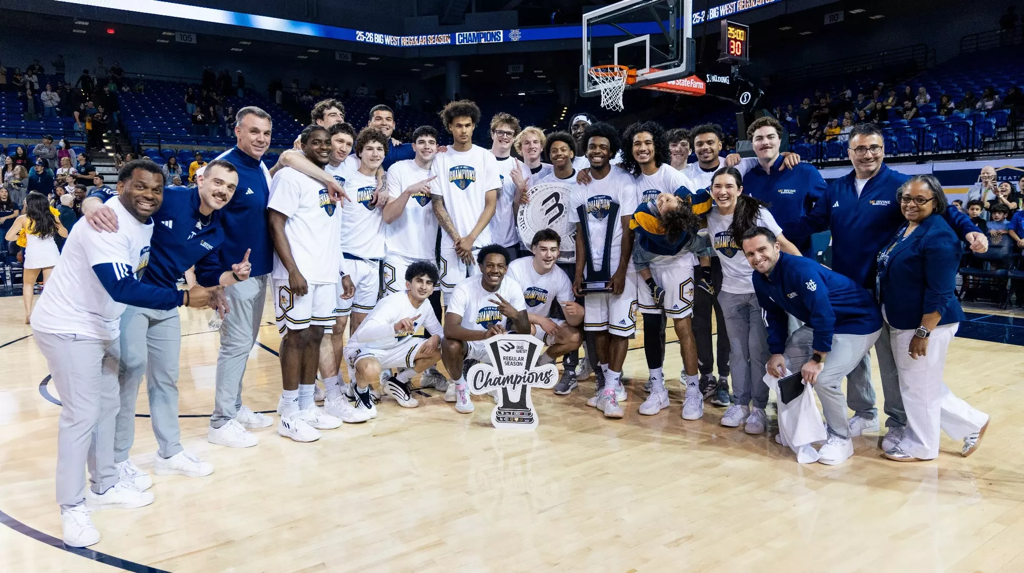 The UC Irvine men's basketball team poses for a photo on the court after winning the Big West regular season championship.