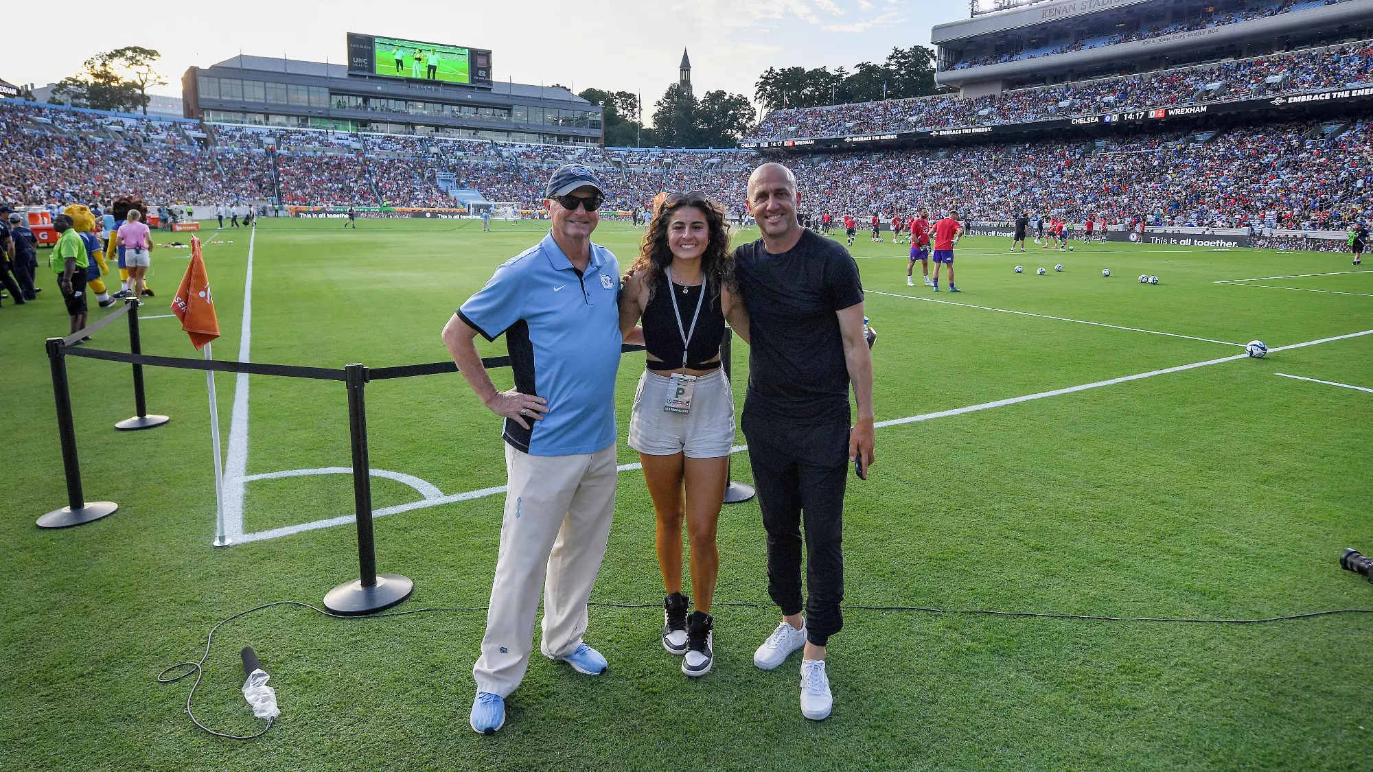 Women's soccer coaches Anson Dorrance, Alex Kimball, and Damon Nahas on the field prior to the Chelsea-Wrexham match.
