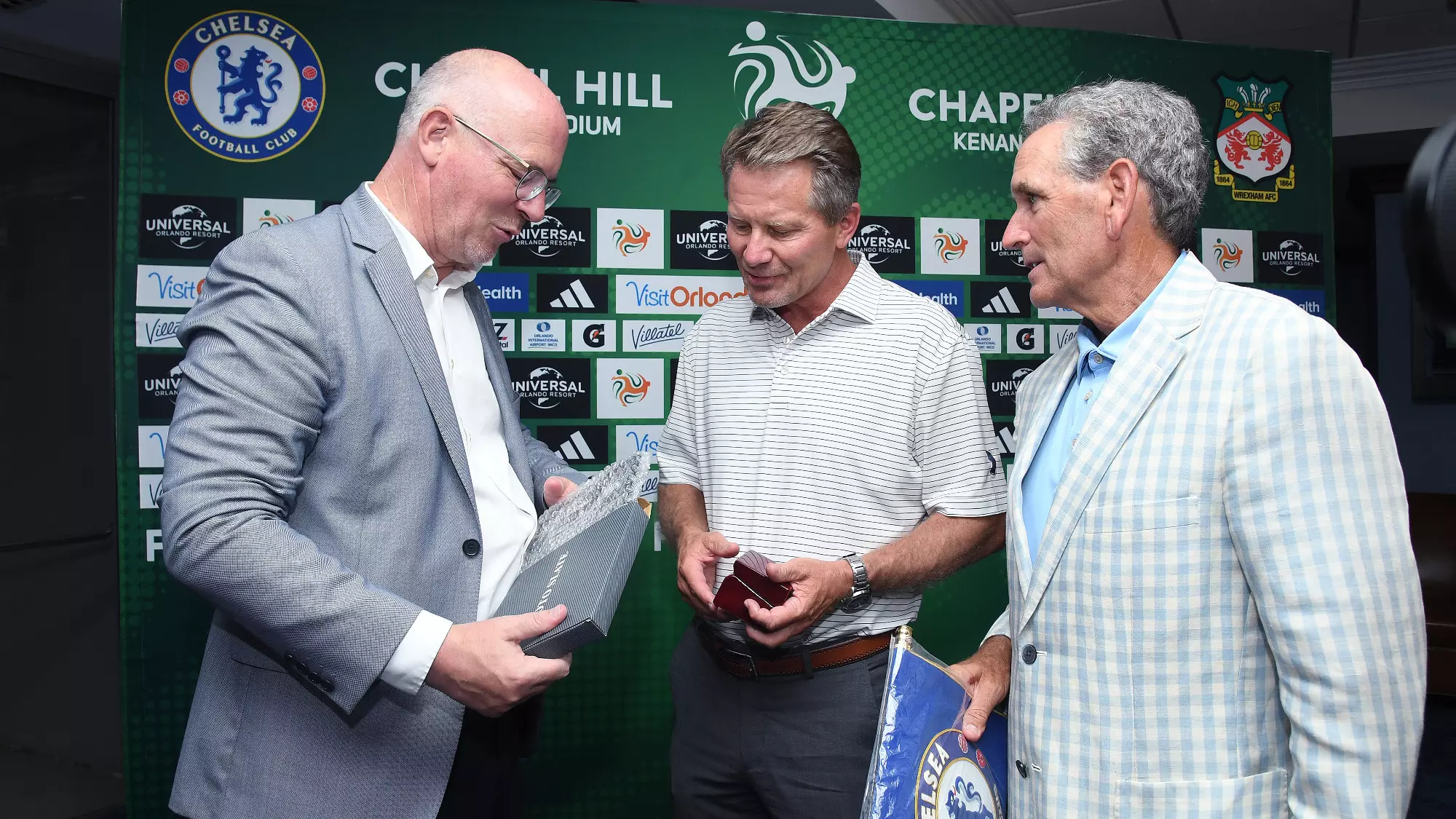 Wrexham's Shaun Harvey presents a gift to UNC Chancellor Kevin Guskiewicz and Athletic Director Bubba Cunningham.