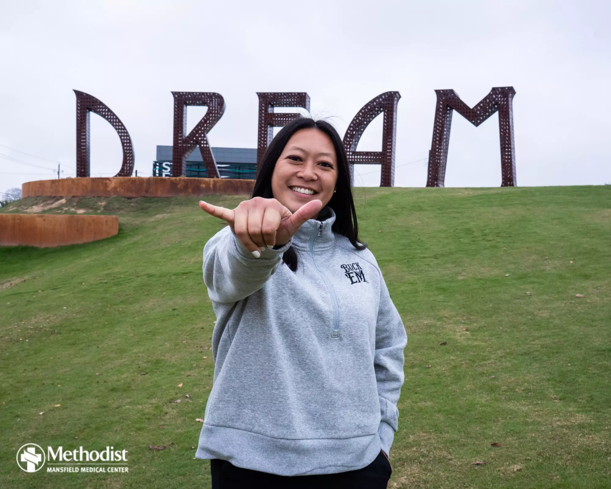 UTA Flag Football Head Coach Melinda Nguyen in front of the Dream City sign downtown in Arlington.