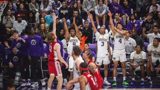 Wesley Yates shoots a three pointer and the bench celebrates during Washington's exhibition with UNLV
