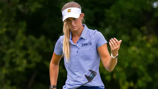 Maggie Carlson eyes her line on the green as she approaches her ball holding her putter in front of her