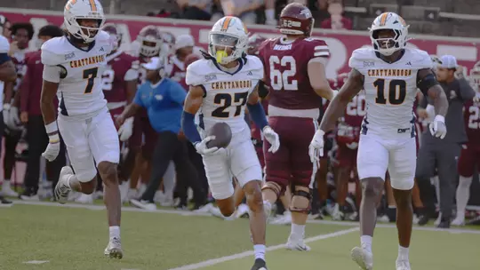 DJ Adams runs off the field carrying the ball after an interception flanked by Keyshawn Jackson and Orlando Daniels.