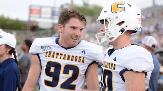 Jude Kelley has his helmet off talking on the sidelines with brother Gray who has his on