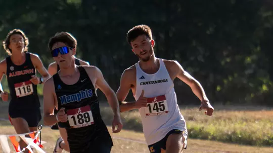 Runners in dark and light uniforms are running a race on a sunny day.