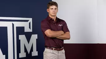 Aaron Pounds poses arms folded in front of a Lone Star Flag themed Texas A&M backdrop