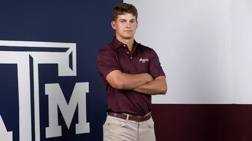 Aaron Pounds poses arms folded in front of a Lone Star Flag themed Texas A&M backdrop