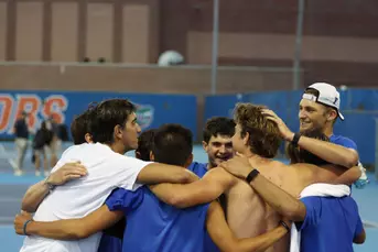 Gators Men's Tennis team celebrating on court five in a huddle after Pablo Perez Ramos clinches the match for the Gators.