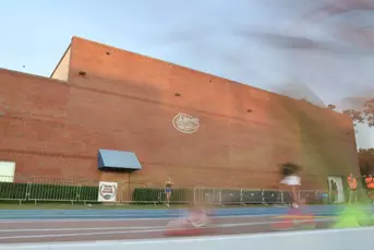 Sunlight hits a brick building with a silver Gators logo