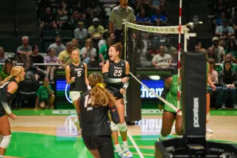 Female athletes in black Florida Gators jerseys celebrate after scoring a point in volleyball