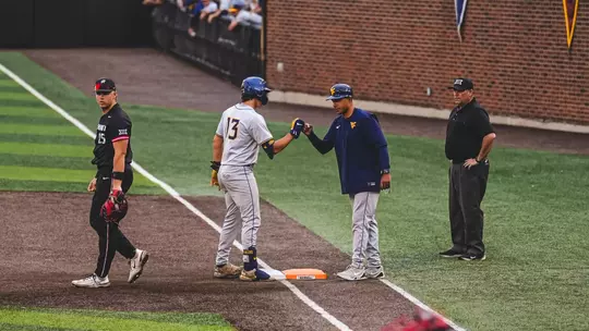 Ryan Maggy fist bumps first base coach Jacob Garcia after hitting a single.
