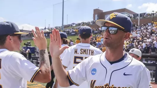 Coach Steve Sabins high-fives a West Virginia University player following the Mountaineers' Super Regional-clinching victory over Cal Poly on June 6, 2026, at Kendrick Family Ballpark in Granville, West Virginia.