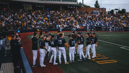 The WVU Baseball Team stands outside the dugout ready to take the field.
