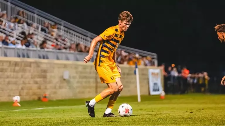 Sebastian Burke dribbles the ball for WVU Men's soccer against George Mason