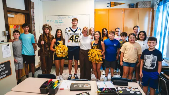 A group of WVU cheerleaders, students and football student-athlete Nate Flower celebrate Extra-Yard-For-Teachers-2026 program