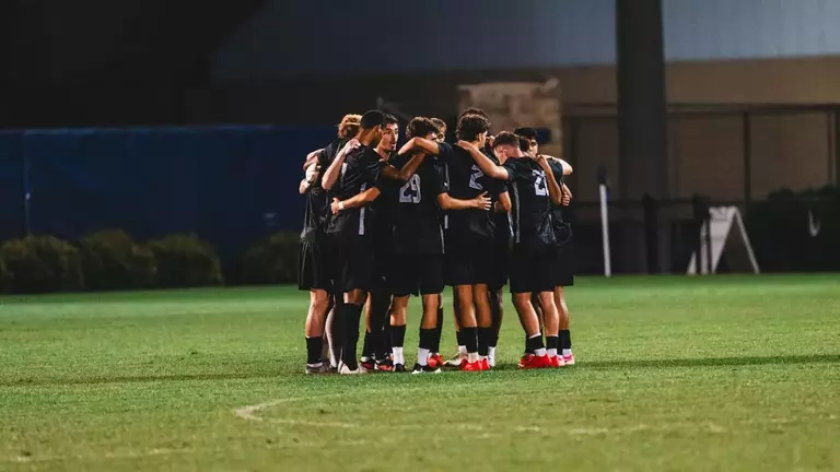 The WVU men's soccer team huddles up in a game against Denver