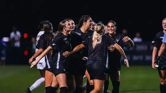 Members of the WVU women's soccer team celebrate after a goal.