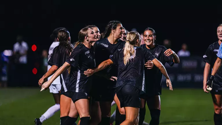 Members of the WVU women's soccer team celebrate after a goal.
