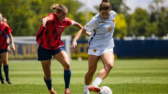 Maya Leoni dribbles a ball during a women's soccer game.